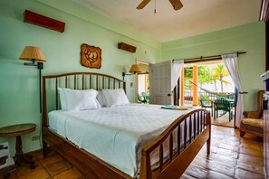 Relax in this serene hotel room featuring a large bed, a small table, and a wall-mounted lamp.