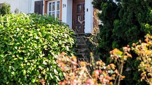 Una casa de dos pisos con balcón, una puerta adornada con un adorno y el número 34 en la pared.