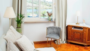 Una sala de estar acogedora con un sofá, un sillón, un aparador de madera y una ventana con cortinas.