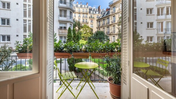 A balcony with a green table and chairs, potted plants, and a view of multi-story buildings. - Paris Chic Trocadero Private apartment in Passy 500 meters from the Eiffel Tower  (Paris)