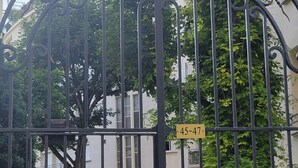 A black wrought iron gate with a sign indicating private property, a number plaque, and a tree in the background. - Paris Chic Trocadero Private apartment in Passy 500 meters from the Eiffel Tower  (Paris)