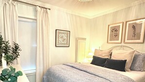 Una camera da letto con un letto, un comodino, una lampada e una finestra con tende.