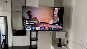 Un téléviseur à écran plat fixé au mur affiche une interface de sélection de films.