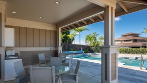 An outdoor patio with a pool, dining area, and a view of a building with a pool.
