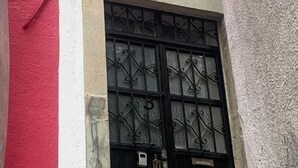 Une ruelle étroite, avec un bâtiment rouge d’un côté et un bâtiment blanc de l’autre. On aperçoit une porte noire sur laquelle est inscrit le chiffre « 5 ».