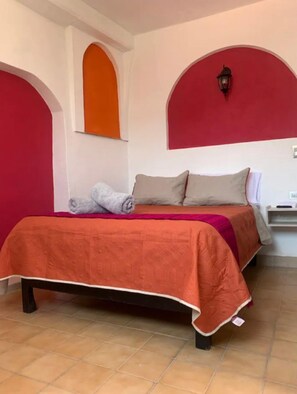 A bed with a red and orange bedspread, a gray blanket, and two pillows. - Garambullo Inn (Guanajuato)