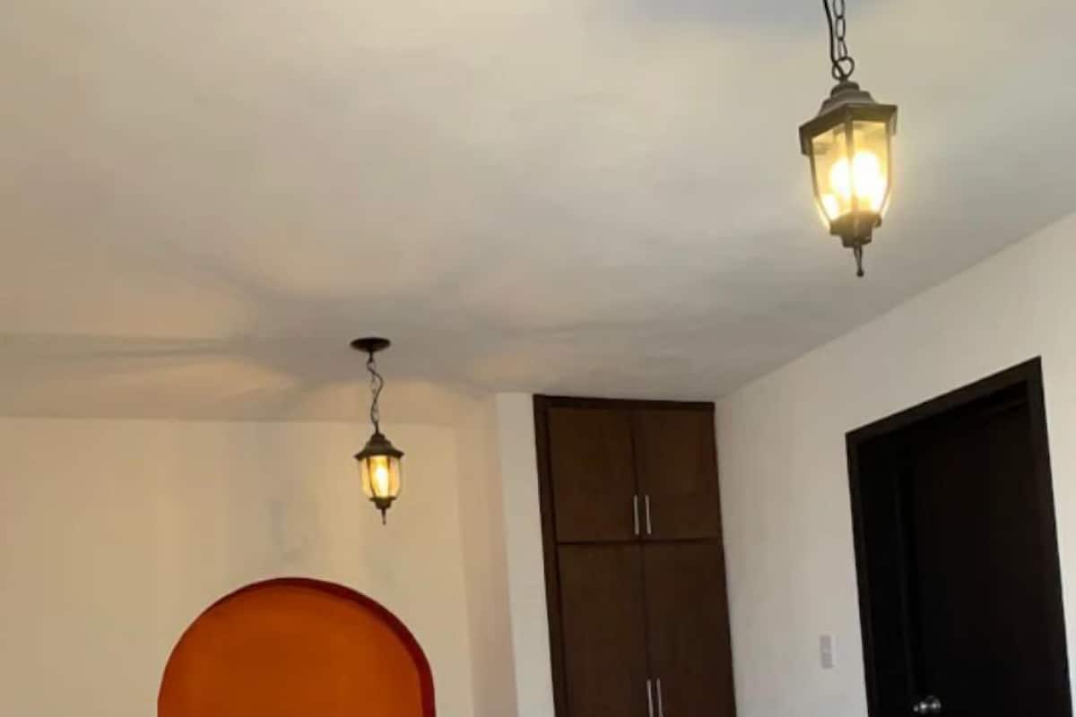 Une chambre avec deux lits, une armoire et deux lampes fixées au mur.