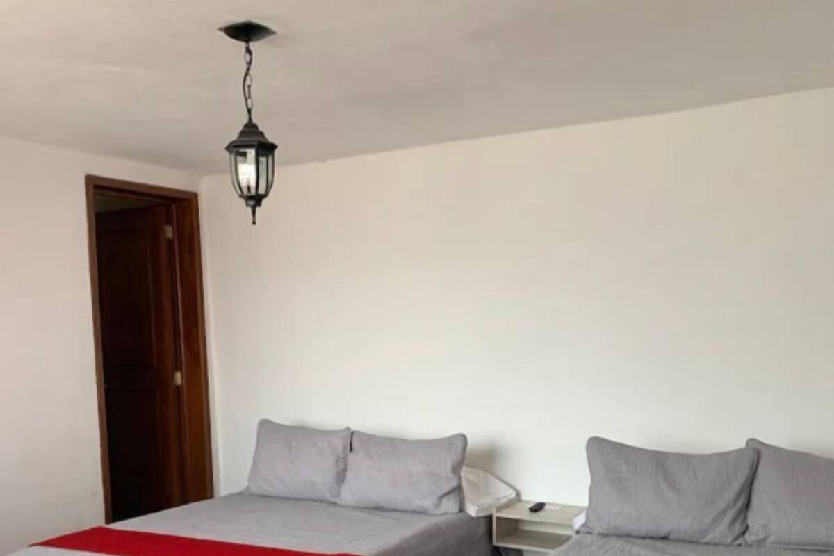 Une chambre avec deux lits, une table de chevet, une lampe et une porte.