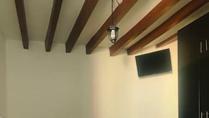 Une chambre à coucher avec un lit, un téléviseur à écran plat fixé au mur et une armoire en bois foncé.