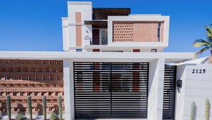 Un bâtiment moderne avec un grand portail noir, un mur de briques orné de cactus et le numéro 2125 sur le côté droit.