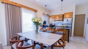 Une cuisine moderne avec des meubles en bois, un plan de travail en marbre et un coin repas comprenant une table et des chaises en bois.