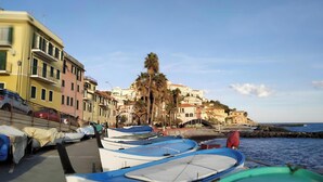 Un pueblo costero con edificios coloridos, barcos amarrados a la orilla y un cielo despejado.