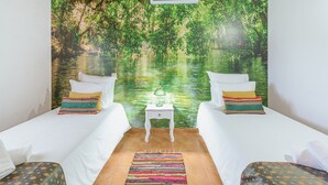 A room with two beds, a small table, a lamp, and a mural of a forest scene. - Holiday Home 'Clarinha' with Mountain View, Wi-Fi and Air Conditioning (Odemira)