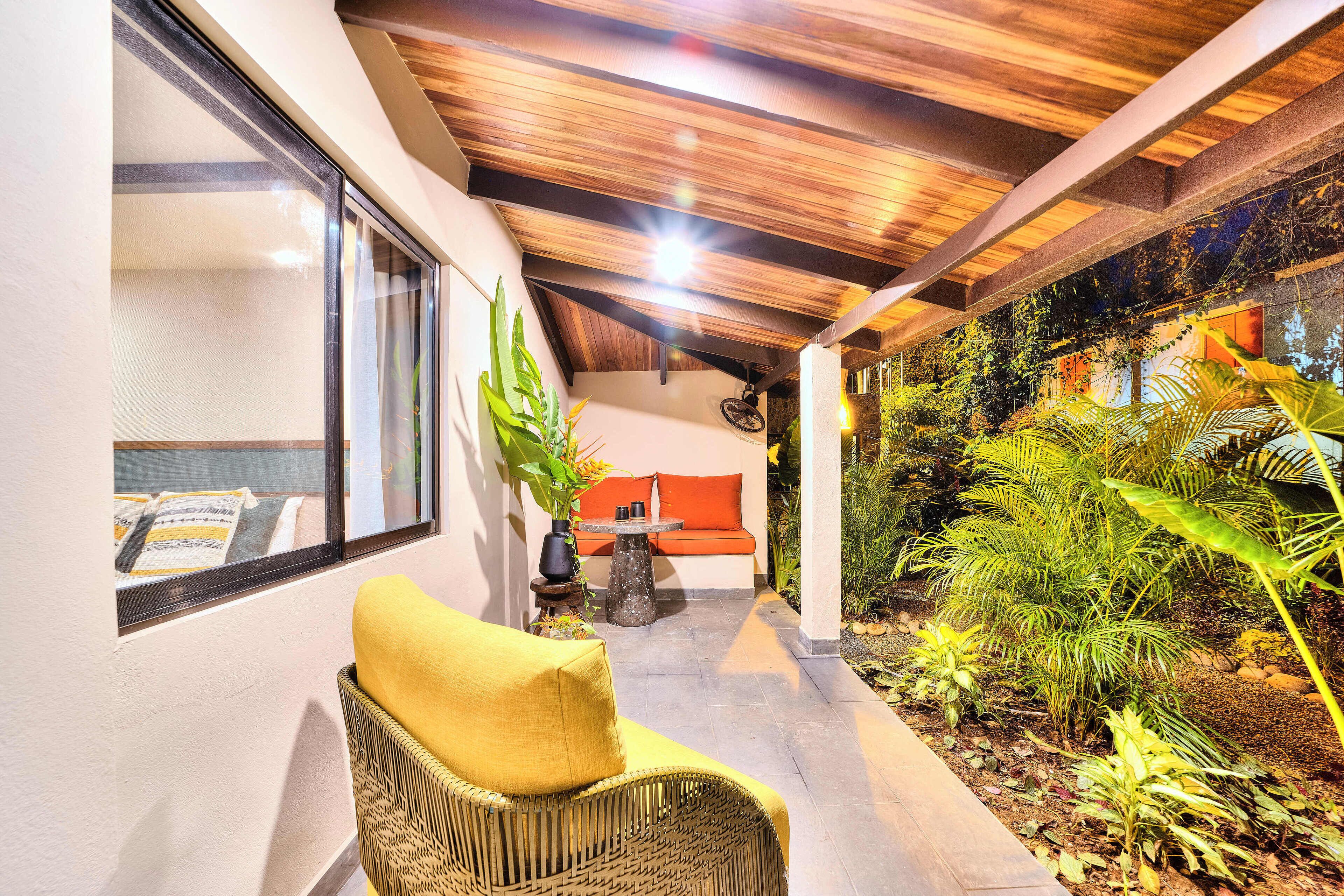 A covered outdoor area with a wicker chair, a table, and a sofa.