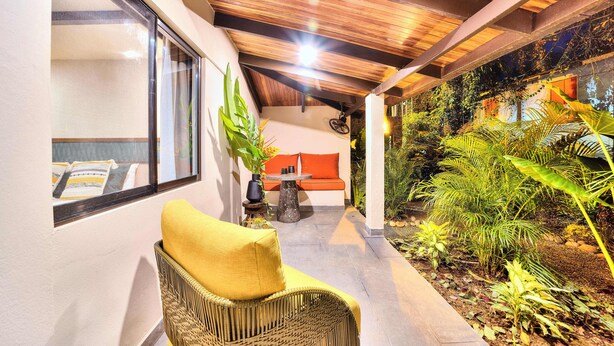 A covered outdoor area with a wicker chair, a table, and a sofa. - Conga Boutique Hotel (Cahuita)