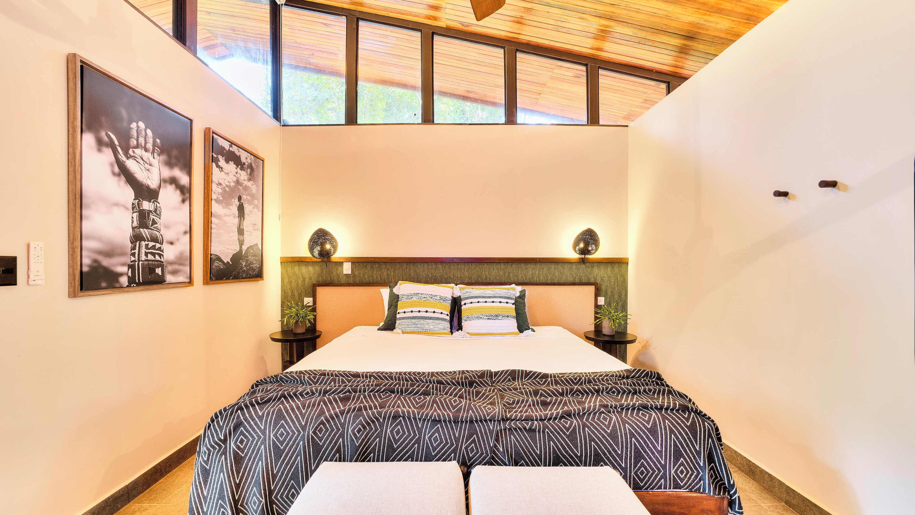 A bedroom with a bed, two bedside tables, a headboard, and a skylight.