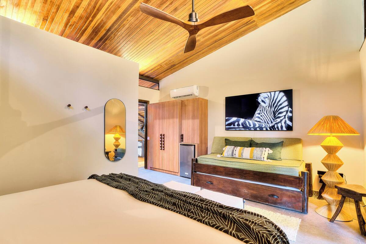 Ein Schlafzimmer mit einem großen Bett, einem Kleiderschrank, einem Fernseher und einem Deckenventilator.