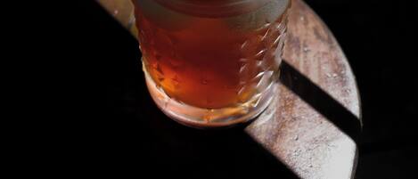 A glass with a beverage and ice cubes on a wooden surface.