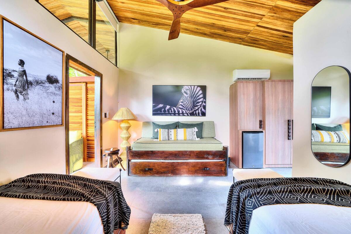 Ein modernes Schlafzimmer mit Bett, Sofa, Spiegel und Kunstwerken an den Wänden.