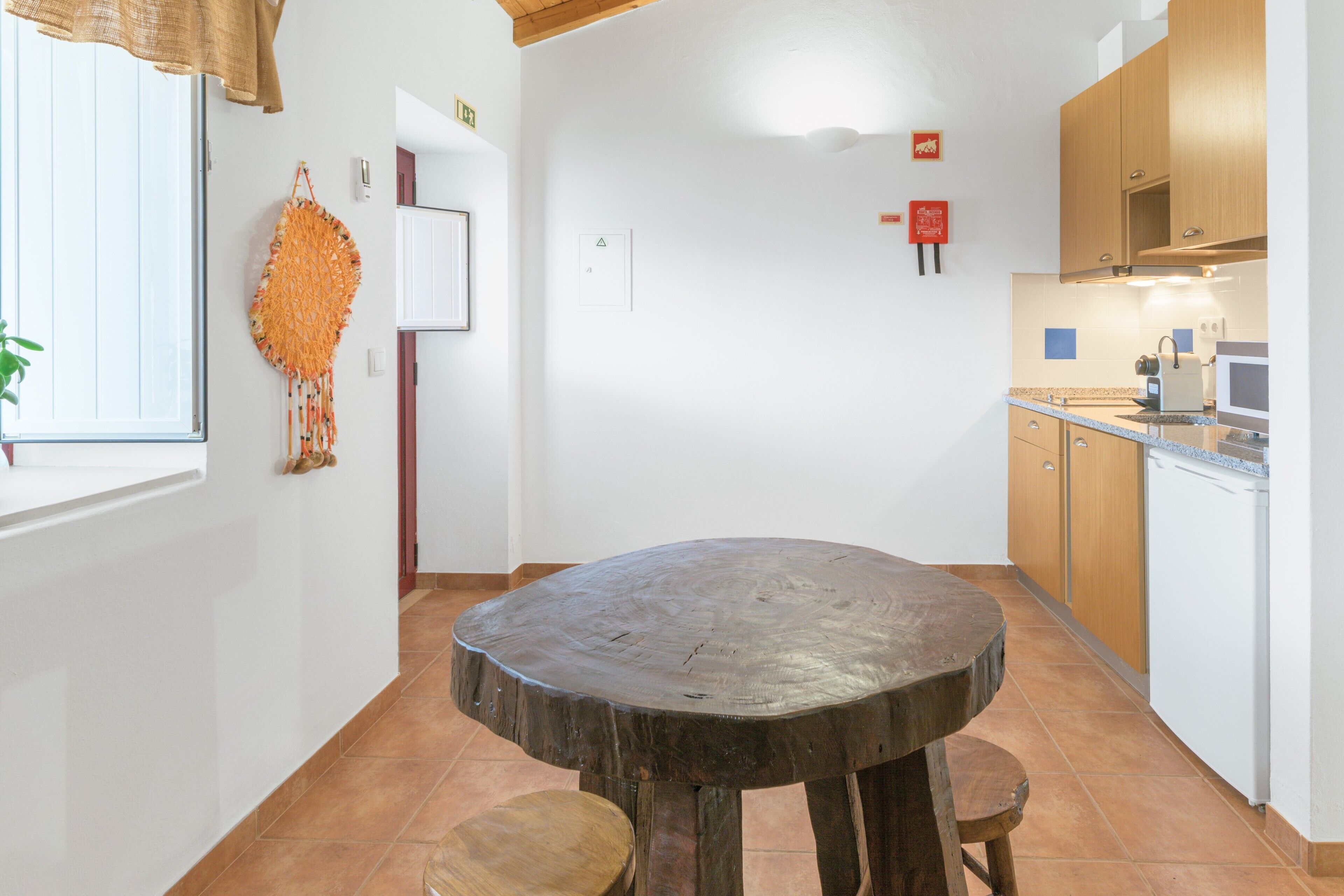 Una cucina con un tavolo rotondo in legno, mobili in legno, una finestra vista e un decoro a parete.