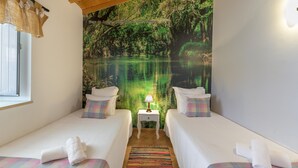A room with two beds, a nightstand with a lamp, and a mural of a forest scene. - Holiday Home 'Rita' with Mountain View, Wi-Fi and Air Conditioning (Odemira)