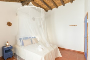 A bed with a mosquito net, a nightstand with a lamp, and a blue door.