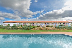 Un hôtel doté d’une piscine, d’un toit recouvert de tuiles rouges et d’une enseigne indiquant la présence d’un restaurant.