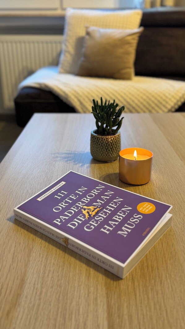 A book titled 'The Ordnance Survey Ordnance Maps' on a wooden table with a lit candle and a small potted plant.