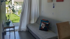 A living room with a sofa, a table, and a potted plant. - Casa Harmonia do Litoral - Florianopolis (Florianópolis)