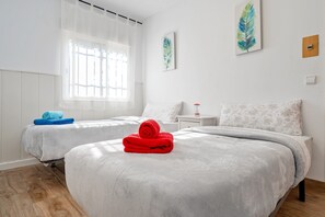 Ein Hotelzimmer mit zwei Betten, einem Fenster mit transparenten Vorhängen und Bildern an den Wänden.