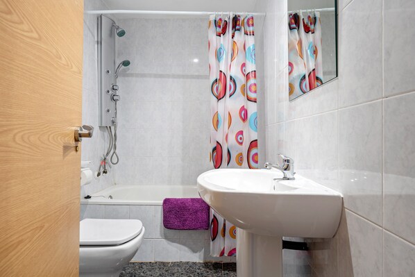 Un baño con ducha, inodoro y lavabo.