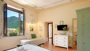 Une chambre d’hôtel avec deux lits, une télévision, une commode et une fenêtre donnant sur une vue sur la montagne.