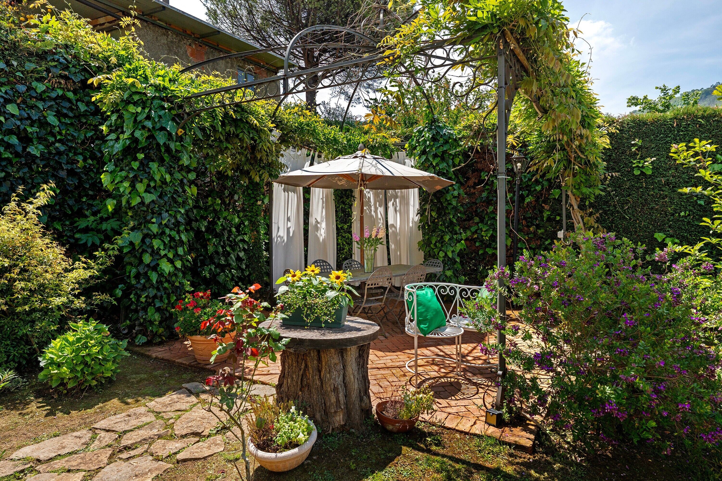 A garden patio with a gazebo, potted plants, and outdoor furniture.