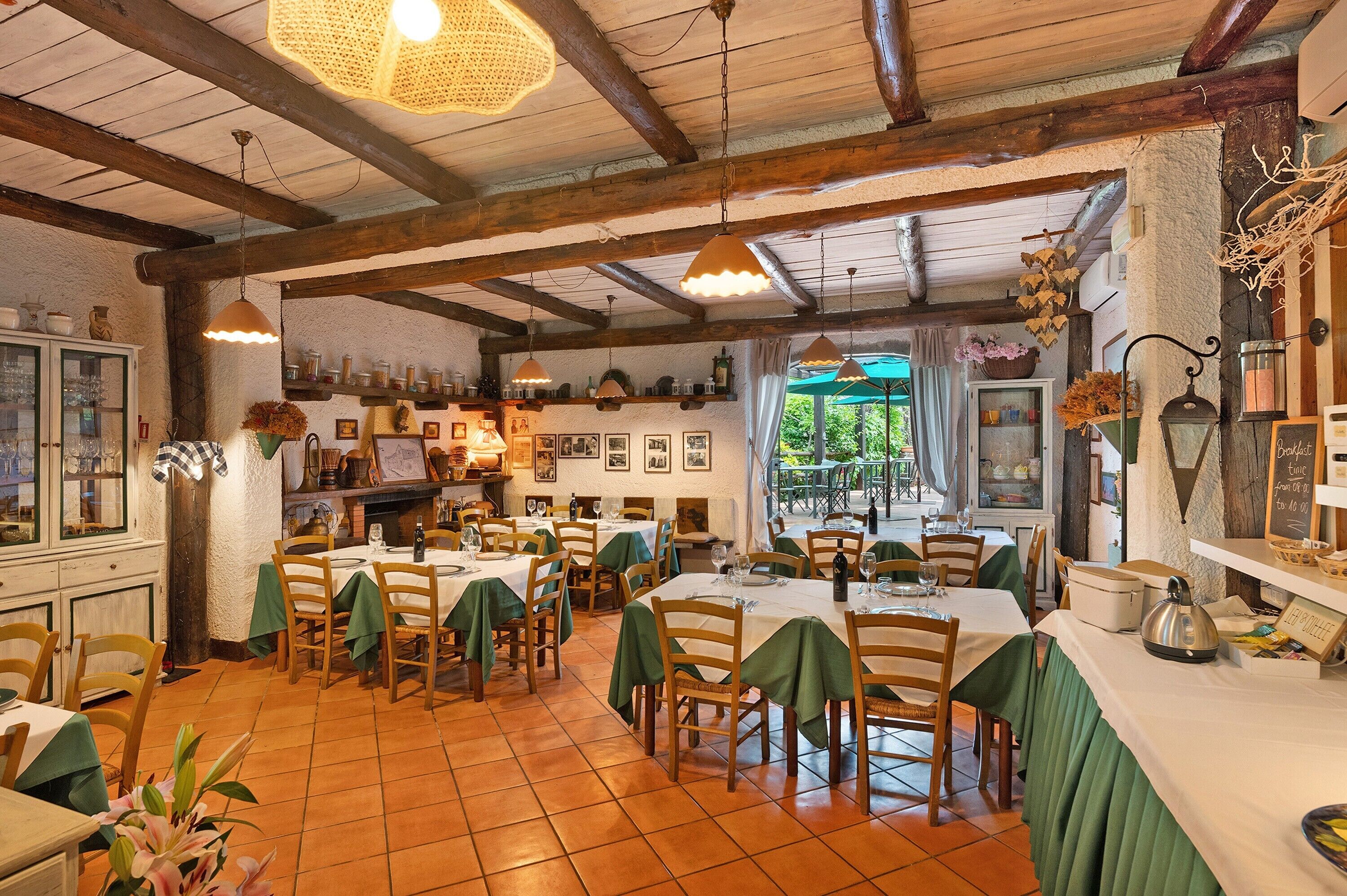 Un restaurante con vigas de madera, manteles verdes y vistas al exterior.