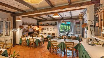 Un restaurante con vigas de madera, manteles verdes y vistas al exterior.