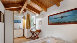 Une pièce comprenant un lit, un bureau, une fenêtre avec des rideaux, un tableau et une vue sur une étendue d’eau.