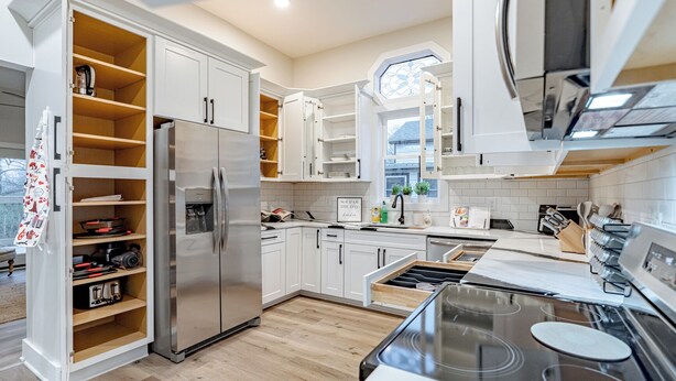 A modern kitchen with white cabinetry, a built-in oven, and a large window.