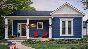 A house with a porch, two red chairs, and a flag.