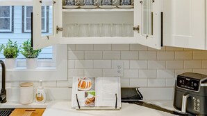 A kitchen with white cabinetry, a coffee maker, a toaster, and a cookbook on the counter.
