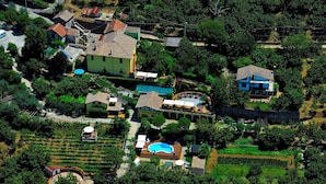 An aerial view of a residential area with houses, a swimming pool, and surrounding greenery.