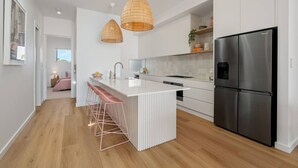 A modern kitchen with a central island, stainless steel appliances, and pendant lighting. - Sunsets ~ Rooftop, Incredible views, 4 KING rooms (Aldinga Beach)