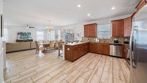 Una cocina amplia con armarios de madera, un refrigerador de acero inoxidable y un comedor con mesa y sillas.