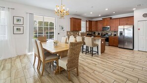 Una cocina moderna con armarios de madera, electrodomésticos de acero inoxidable y un comedor con sillas de mimbre y una mesa de madera.