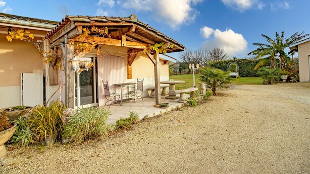 A house with a pergola covered in vines, a patio with a table and chairs, and a gravel driveway. - Escape to Les Pouges – Renovated House with Garden, Fast Wi-Fi, Barbecue (Saint Avit Saint Nazaire)