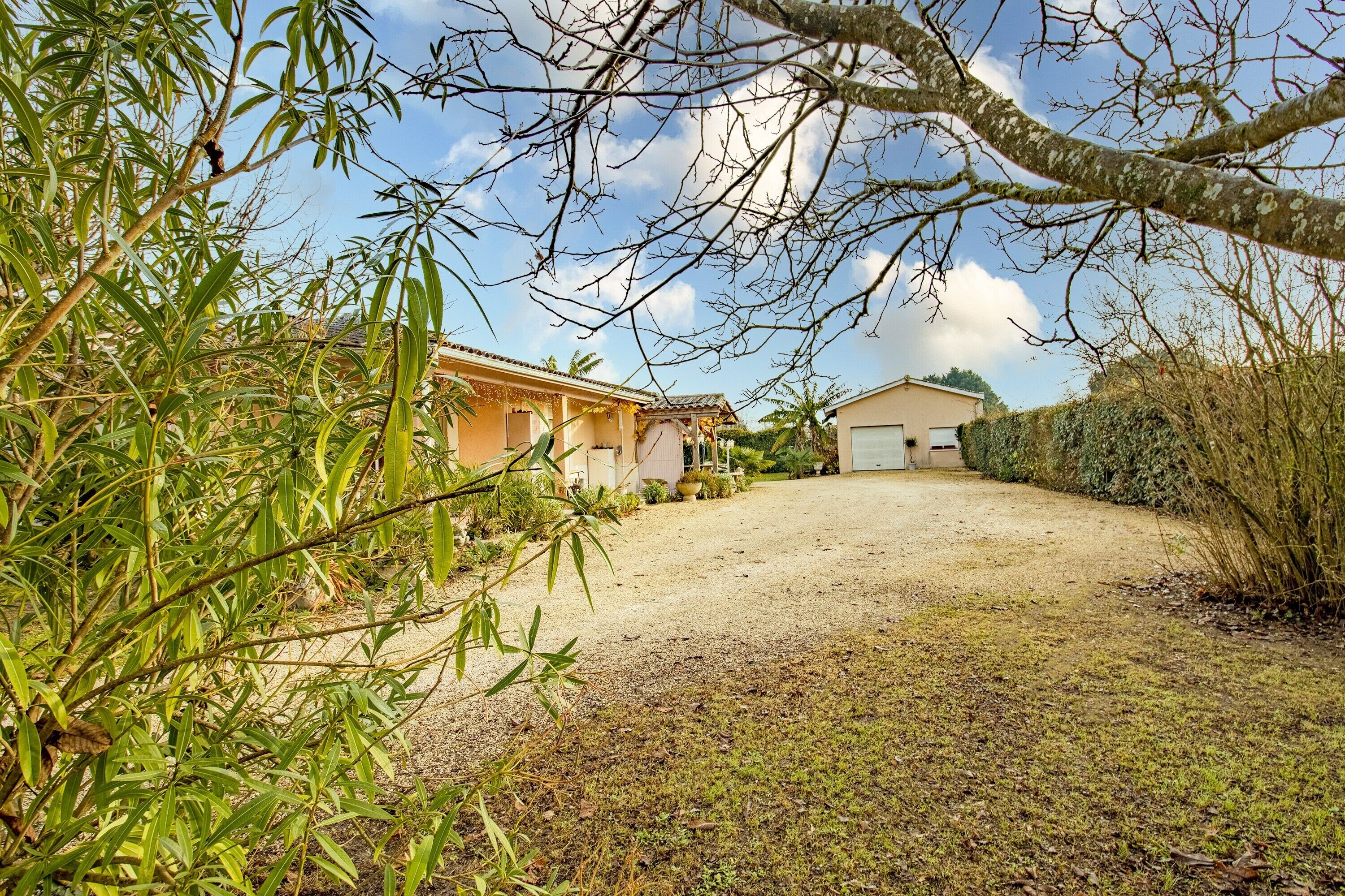 Um imóvel residencial com entrada por caminho de pedras, uma casa com telhado em cerâmica e vegetação ao redor.