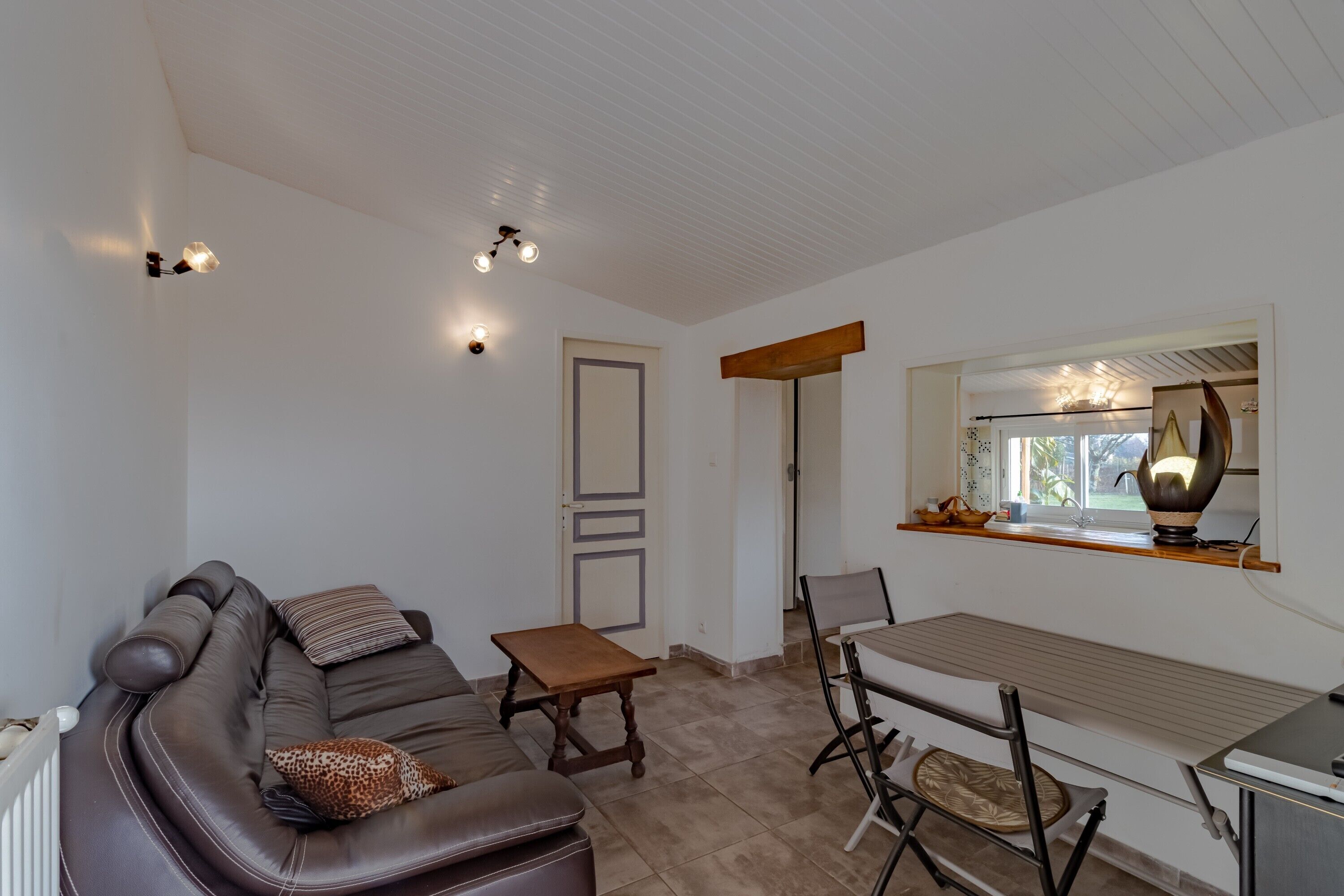 Una sala de estar con un sofá, una mesa de madera y un comedor con sillas.