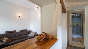 A modern living room with a wooden coffee table, a dark leather sofa, and a glass shower door leading to a tiled bathroom. - Escape to Les Pouges – Renovated House with Garden, Fast Wi-Fi, Barbecue (Saint Avit Saint Nazaire)