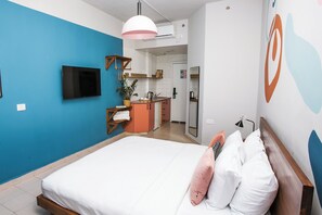A bedroom with a bed, a TV, a kitchen area, and a bathroom. - Domus Tlv (Tel Aviv)