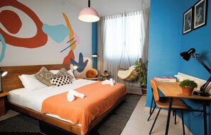 A modern hotel room with a large bed, a desk, a chair, a hanging chair, and a large abstract painting on the wall. - Domus Tlv (Tel Aviv)