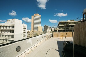 Una terraza en la azotea con vistas a un horizonte urbano, destacando un edificio con aguja.